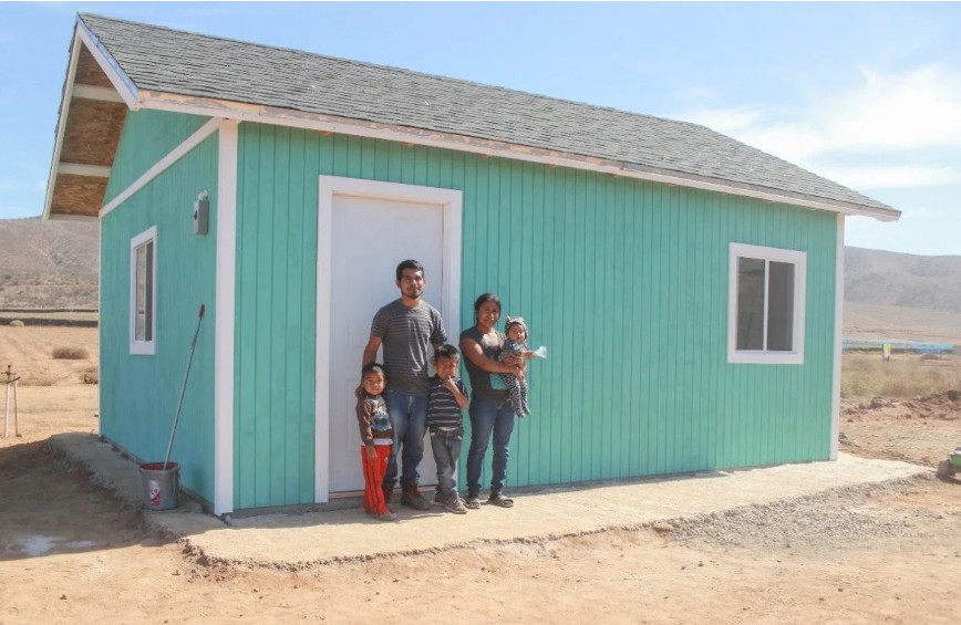 A family standing in front of their newly built home.